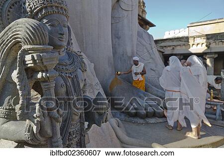 "Jain pilgrims doing a special pooja in front of the gigantic statue to receive the blessings of Bahubali by the local priests, Sravanabelagola, India, Asia" View Large Photo Image Stock Photo - "Jain pilgrims doing a special pooja in front of the gigantic statue to receive the blessings of Bahubali by the local priests, Sravanabelagola, India, Asia". Fotosearch