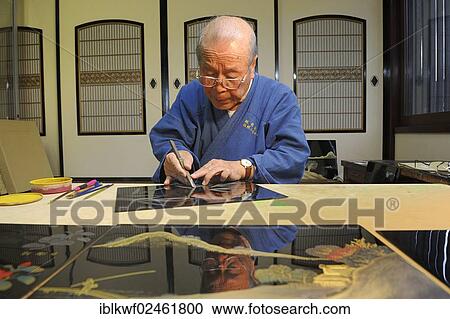 Stock Image - "Japanese artisan scraping a bamboo motif onto the top lacquer coat, Sabae, Fukui, Japan, East Asia, Asia". Fotosearch