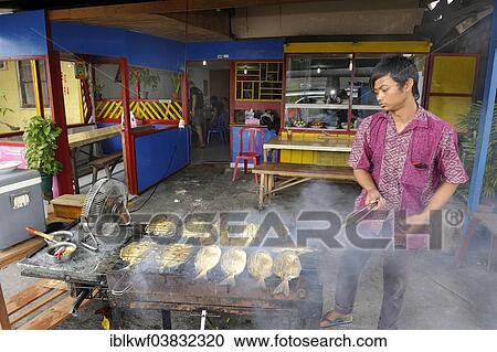 "Javanese man grilling fish in a restaurant, Biak city, Biak Island, West Papua, Indonesia, Asia" View Large Photo Image Stock Image - "Javanese man grilling fish in a restaurant, Biak city, Biak Island, West Papua, Indonesia, Asia". Fotosearch