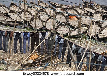 Stock Photo - "Jeans hanging to dry on clotheslines in front of boats on the bank of the Buriganga River, Dhaka, Bangladesh, South Asia, Asia". Fotosearch