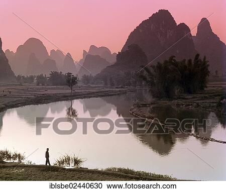 "Karst mountain landscape, man standing beside the Yulong River, Yangshuo, Li Jiang River, Guilin, Guangxi, China, Asia" View Large Photo Image Stock Image - "Karst mountain landscape, man standing beside the Yulong River, Yangshuo, Li Jiang River, Guilin, Guangxi, China, Asia". Fotosearch