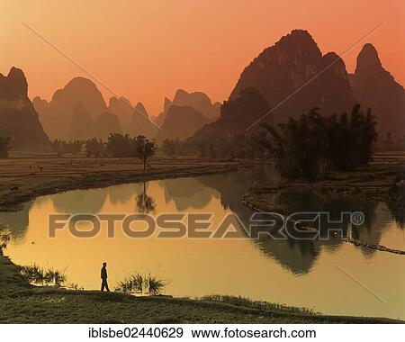 "Karst mountain landscape, man standing beside the Yulong River, Yangshuo, Li Jiang River, Guilin, Guangxi, China, Asia" View Large Photo Image Stock Photo - "Karst mountain landscape, man standing beside the Yulong River, Yangshuo, Li Jiang River, Guilin, Guangxi, China, Asia". Fotosearch