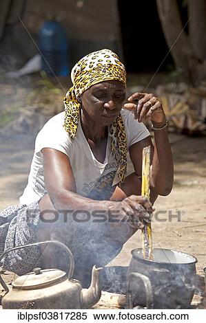 Stock Photography - "Kavango woman preparing the traditional Ugali maize flour dish on a campfire, Okavango Delta, Botswana, Africa". Fotosearch