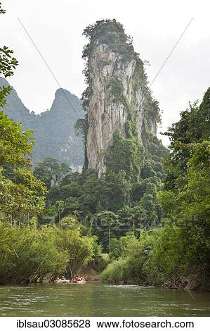 Stock Photo - "Kayakers rowing on a river through the jungle, karst landscape with a pinnacle rock towering above them, beim Kao Sok Nationalpark, Provinz Surat Thani, Thailand, Asia". Fotosearch
