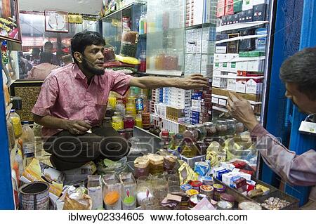 Stock Photography - "Kiosk vendor passing cigarettes to a customer, Dhaka, Bangladesh, South Asia, Asia". Fotosearch