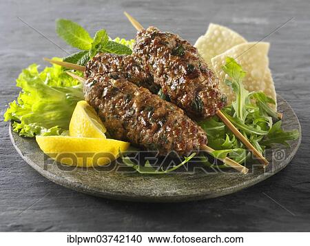 Stock Image - Kofte kebabs with salad and lemon wedges. Fotosearch