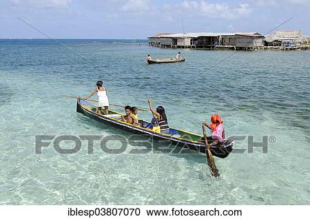 Stock Image - "Kuna Indians in a dugout canoe, Nalunega, San Blas Islands, Caribbean, Panama, North America". Fotosearch