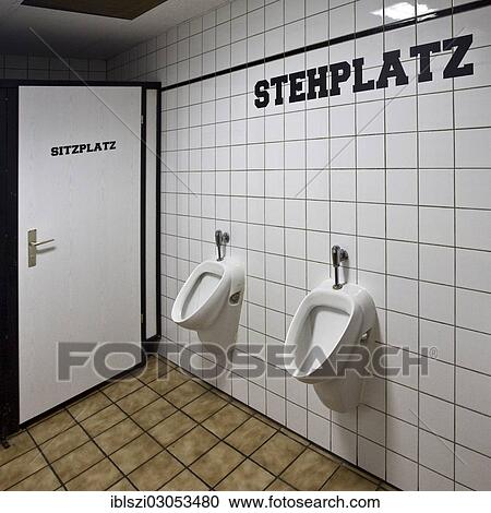 Stock Image - "Lettering """"Stehplatz"""", German for """"standing room"""" above the urinals and the lettering """"Sitzplatz"""", German for """"seat"""" on the door of a men's toilet, Germany, Europe". Fotosearch