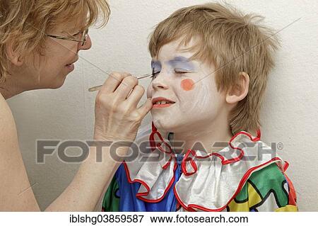 Stock Photo - "Little boy dressed as a clown, is made up by his mother". Fotosearch