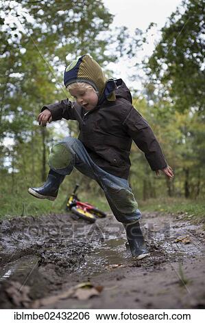 "Little boy jumping with joy into a muddy puddle during an autumn walk, Brandenburg, Germany, Europe" View Large Photo Image Stock Photograph - "Little boy jumping with joy into a muddy puddle during an autumn walk, Brandenburg, Germany, Europe". Fotosearch