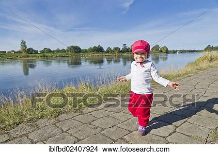 Picture - "Little girl, 14 months, doing her first steps on a footpath on a riverbank along the Elbe river, Dresden, Saxony, Germany, Europe". Fotosearch