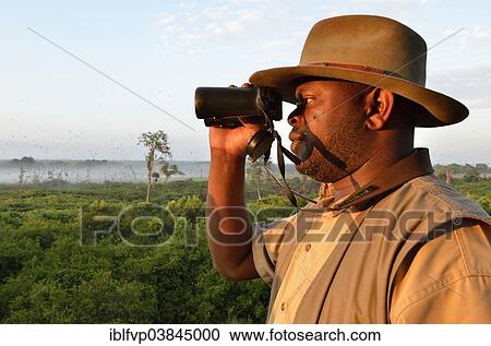 Stock Image - "Local man looking through binoculars, Kasanka National Park, Zambia, Africa". Fotosearch