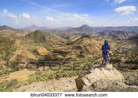 Stock Photo - "Local woman standing on a rock in front of the mountain scenery along the road from Massawa to Asmarra, Eritrea, Africa". Fotosearch