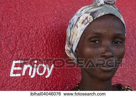 "Local woman with a headscarf in front of a red wall with the lettering """"Enjoy"""", portrait, Outjo, Namibia, Africa" View Large Photo Image Stock Photograph - "Local woman with a headscarf in front of a red wall with the lettering """"Enjoy"""", portrait, Outjo, Namibia, Africa". Fotosearch