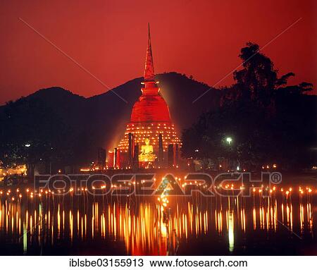 Stock Image - "Loi Krathong Festival, Wat Sra Si illuminated with red lights, torches reflecting in the water, Sukhothai Historical Park, Sukhothai, Sukhothai Province, Northern Thailand, Thailand, Asia". Fotosearch