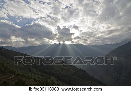 Stock Image - "Looking across the Deku Kola Valley, setting sun behind dramatic clouds, Kharikhola, Solukhumbu District, Sagarmatha Zone, Nepal, Asia". Fotosearch