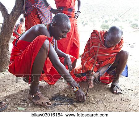 Picture - "Maasai warriors wearing traditional dress starting a fire with a fire stick, Massai Mara, Distrikt Narok, Serengeti, Rift Valley province, Kenya, Africa". Fotosearch