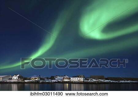 Stock Image - "Majestic green aurora formation, Aurora borealis, Northern Lights, above a row of houses against a blue night sky, Lofoten, Svolvaer, Nordland, Northern Norway, Norway, Europe". Fotosearch