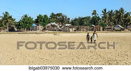 Stock Image - "Malagasy woman and her two children walking on the beach, Betany village, Morondava, Toliara province, Madagascar, Africa". Fotosearch