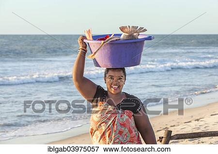 Stock Photo - "Malagasy woman carrying fish in a tub on her head, Morondava, Toliara province, Madagascar, Africa". Fotosearch