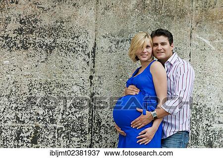 Stock Photo - Man and a pregnant woman holding their hands on her belly. Fotosearch