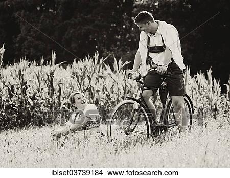 Picture - "Man and a woman wearing traditional costume with an old bicycle within a natural landscape, Aldrans, Tyrol, Austria, Europe". Fotosearch