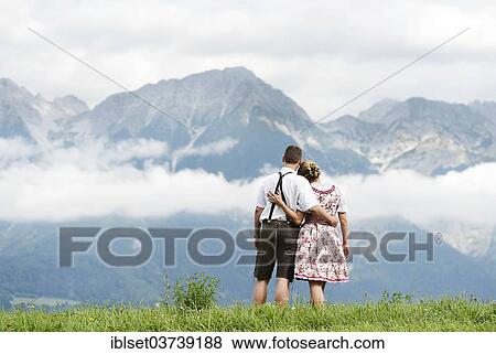 Stock Photo - "Man and a woman wearing traditional costume looking towards the mountains, Aldrans, Tyrol, Austria, Europe". Fotosearch