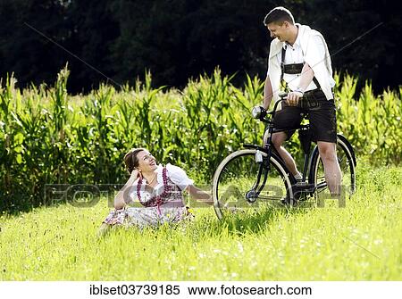 Stock Photography - "Man and a woman wearing traditional costume with an old bicycle within a natural landscape, Aldrans, Tyrol, Austria, Europe". Fotosearch
