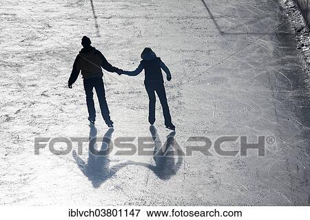 Stock Photo - "Man and woman holding hands ice skating, Achental Valley, Achenkirch, North Tyrol, Austria, Europe". Fotosearch