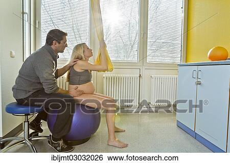 Man And Woman In The Delivery Room During Childbirth The Woman Is Sitting On A Ball During Labour Germany Europe Stock Photograph