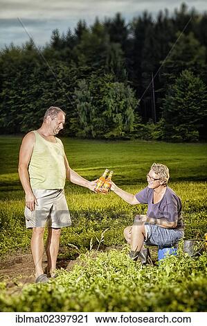 Stock Image - Man and woman taking a bread during their work on a field. Fotosearch