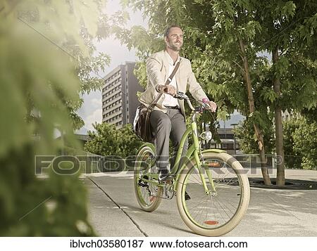 "Man carrying a bag over his shoulder while riding a bicycle in the park, Innsbruck, Tyrol, Austria, Europe" View Large Photo Image Stock Photo - "Man carrying a bag over his shoulder while riding a bicycle in the park, Innsbruck, Tyrol, Austria, Europe". Fotosearch