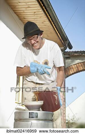 Stock Photo - Man filling apple juice into a pressure barrel. Fotosearch