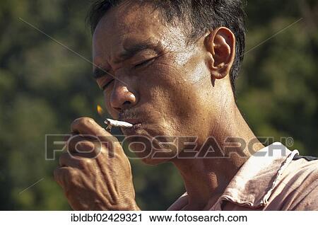 "Man from the Shan or Thai Yai ethnic minority is lighting a cigarette, Soppong or Pang Mapha area, Northern Thailand, Thailand, Asia" View Large Photo Image Stock Image - "Man from the Shan or Thai Yai ethnic minority is lighting a cigarette, Soppong or Pang Mapha area, Northern Thailand, Thailand, Asia". Fotosearch