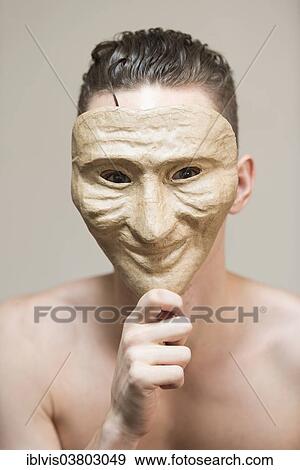Stock Photo - Man hiding behind a happy mask. Fotosearch
