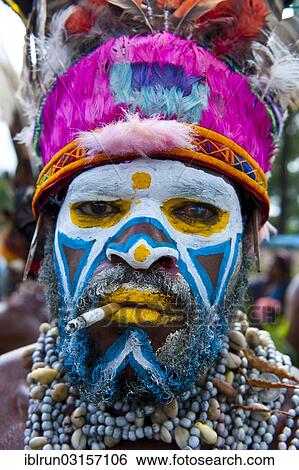 "Man in a colourfully decorated costume with face paint and a cigarette at the traditional sing-sing gathering, Hochland, Mount Hagen, Western Highlands Province, Papua New Guinea, Oceania" View Large Photo Image Stock Photograph - "Man in a colourfully decorated costume with face paint and a cigarette at the traditional sing-sing gathering, Hochland, Mount Hagen, Western Highlands Province, Papua New Guinea, Oceania". Fotosearch