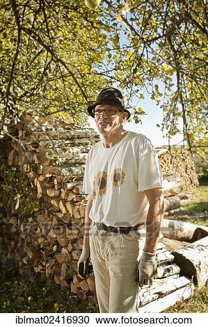 Man in the orchard in front of a wood pile View Large Photo Image Stock Image - Man in the orchard in front of a wood pile. Fotosearch