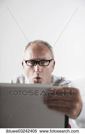 "Man looking at a tablet PC with a stunned expression, Mannheim, Baden-Wurttemberg, Germany, Europe" View Large Photo Image Stock Photography - "Man looking at a tablet PC with a stunned expression, Mannheim, Baden-Wurttemberg, Germany, Europe". Fotosearch