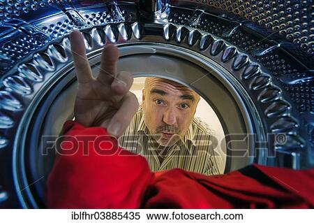 "Man looking into a washing machine, grabbing a red cloth, Germany, Europe" View Large Photo Image Stock Photography - "Man looking into a washing machine, grabbing a red cloth, Germany, Europe". Fotosearch