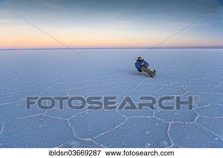 "Man lying on a deck chair on the parched salt lake of Salar de Uyuni at dusk, Uyuni, Bolivia, South America" View Large Photo Image Stock Photo - "Man lying on a deck chair on the parched salt lake of Salar de Uyuni at dusk, Uyuni, Bolivia, South America". Fotosearch