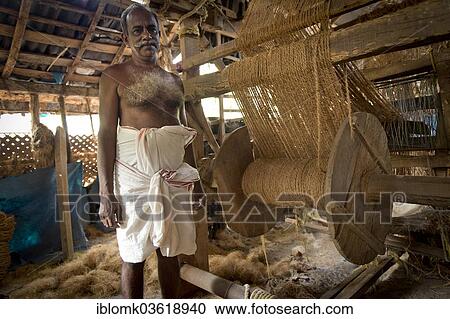 Stock Image - "Man making ropes from coconut fibres in a small business, Vembanad lake, Kerala, India, Asia". Fotosearch