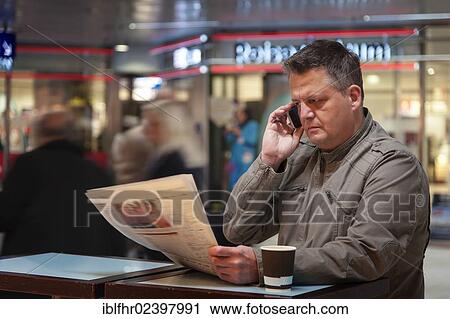 "Man on a mobile phone reading a newspaper, Duesseldorf, North Rhine-Westphalia, Germany, Europe" View Large Photo Image Stock Image - "Man on a mobile phone reading a newspaper, Duesseldorf, North Rhine-Westphalia, Germany, Europe". Fotosearch