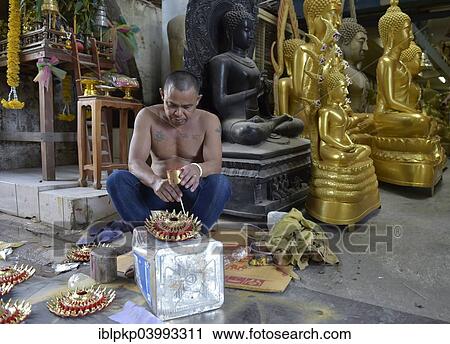 Stock Image - "Man painting parts of a Buddha statue, Bangkok, Thailand, Asia". Fotosearch