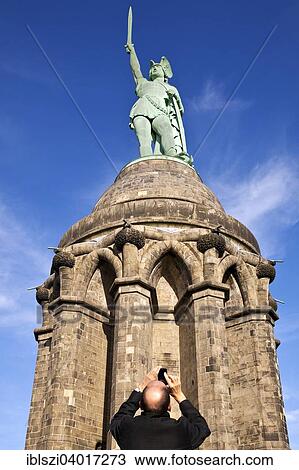 Stock Image - "Man photographing the Hermannsdenkmal monument, Detmold, Ostwestfalen-Lippe, North Rhine-Westphalia, Germany, Europe". Fotosearch