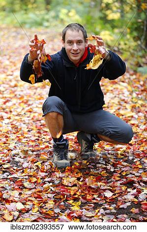 Stock Photo - "Man playing with autumn leaves, the Adirondacks, Upstate New York, USA". Fotosearch