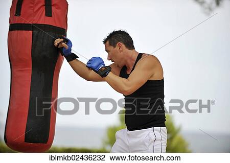 Man practicing punches on a punching bag in a park View Large Photo Image Stock Image - Man practicing punches on a punching bag in a park. Fotosearch