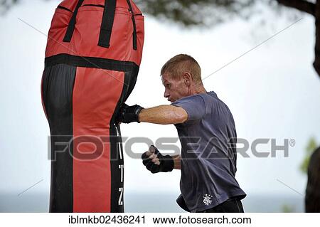 Man practicing punches on a punching bag in a park View Large Photo Image Stock Image - Man practicing punches on a punching bag in a park. Fotosearch