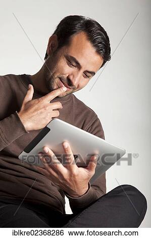 Man reading on an iPad View Large Photo Image Stock Photograph - Man reading on an iPad. Fotosearch