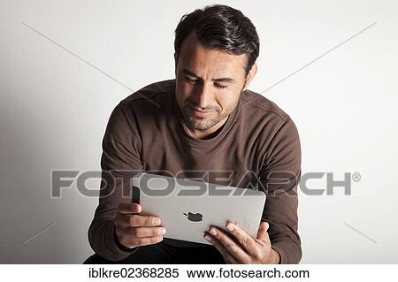 Man reading on an iPad View Large Photo Image Stock Photography - Man reading on an iPad. Fotosearch