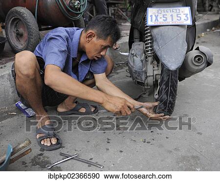 Man repairing a flat tyre of his motorbike View Large Photo Image Stock Image - Man repairing a flat tyre of his motorbike. Fotosearch